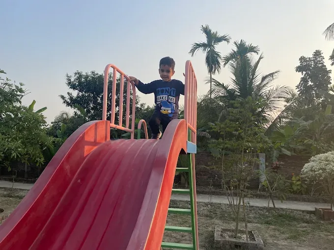 A young boy standing at the top of a red slide