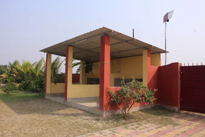 Yellow and red covered shelter with a flowering bush beside the entrance gate