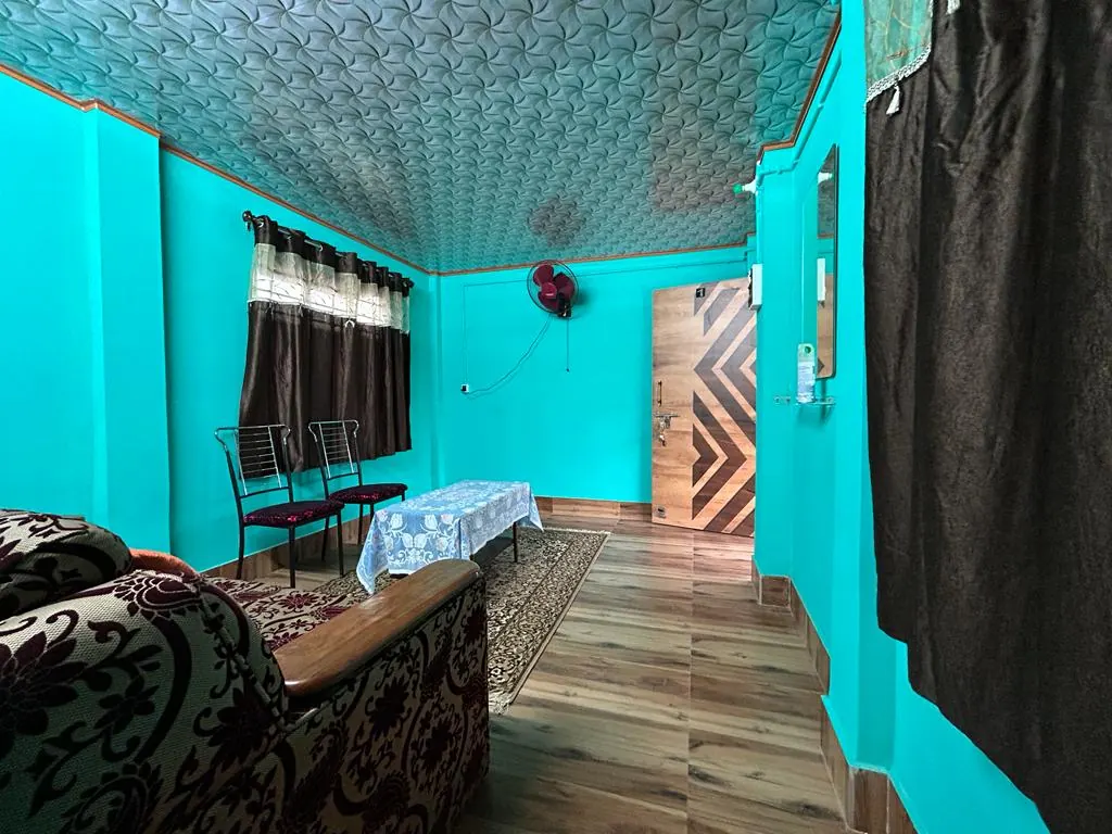 Furnished room with turquoise walls, a sofa, two chairs and a covered table