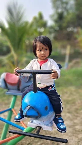 A small child sitting on a blue rocker ride